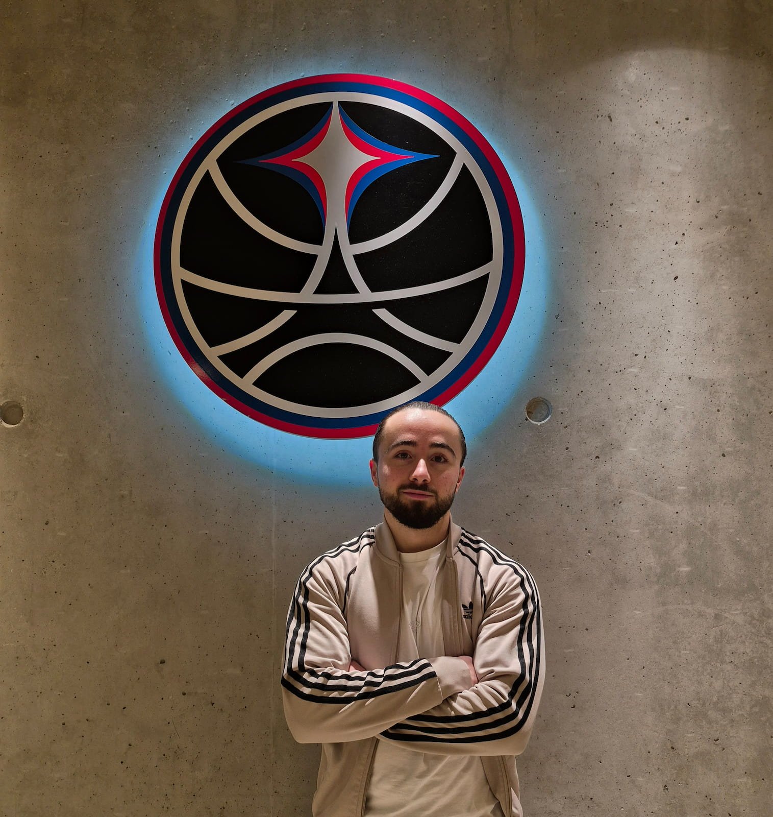 Mathis Bruguiere diététicien posant devant le logo du Paris Basketball dans l'Adidas Arena