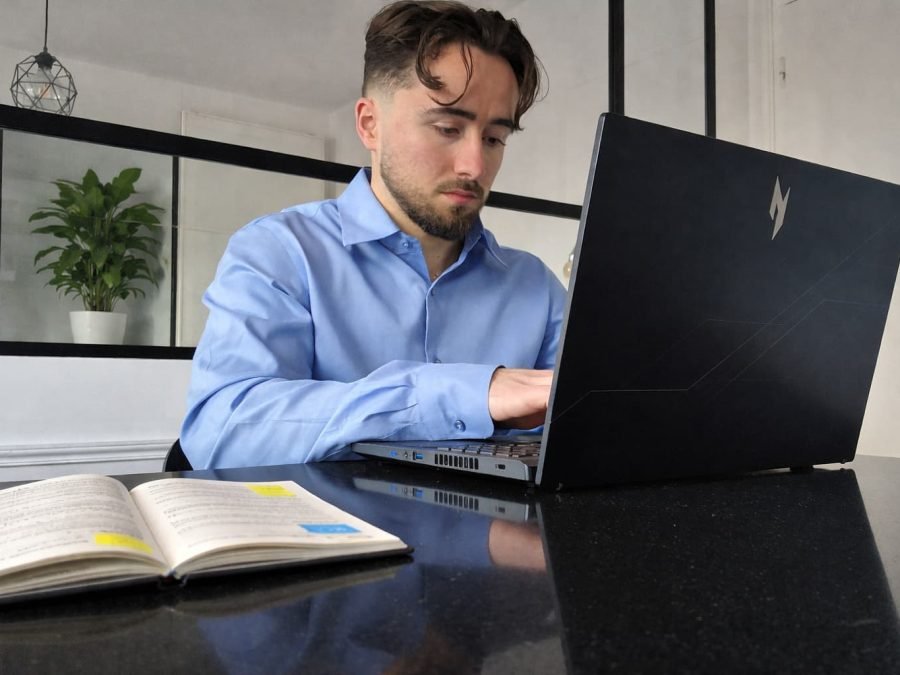 diététicien Mathis Bruguiere en consultation diététique en ligne en train de taper sur un ordinateur avec un carnet sur la table et une plante en arrière-plan